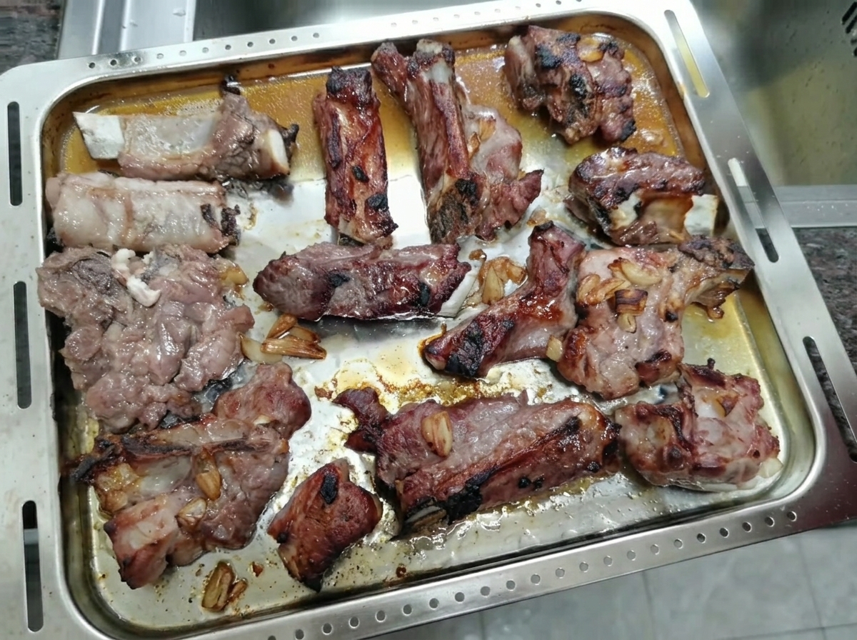 Upieczone, skarmelizowane żeberka wieprzowe stygnące na metalowej blasze.
