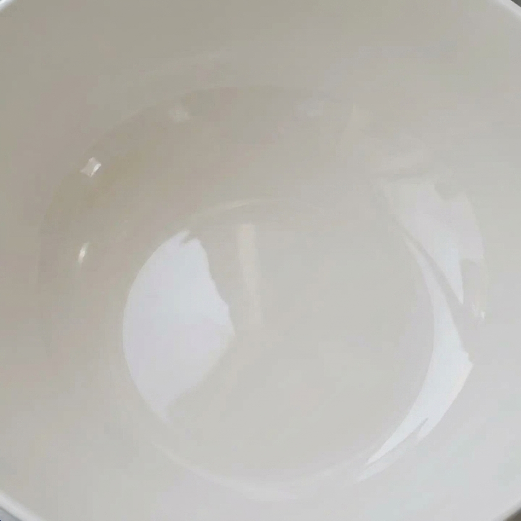 Świeże małże moczące się w białej misce wypełnionej czystą wodą, gotowe do oczyszczenia.