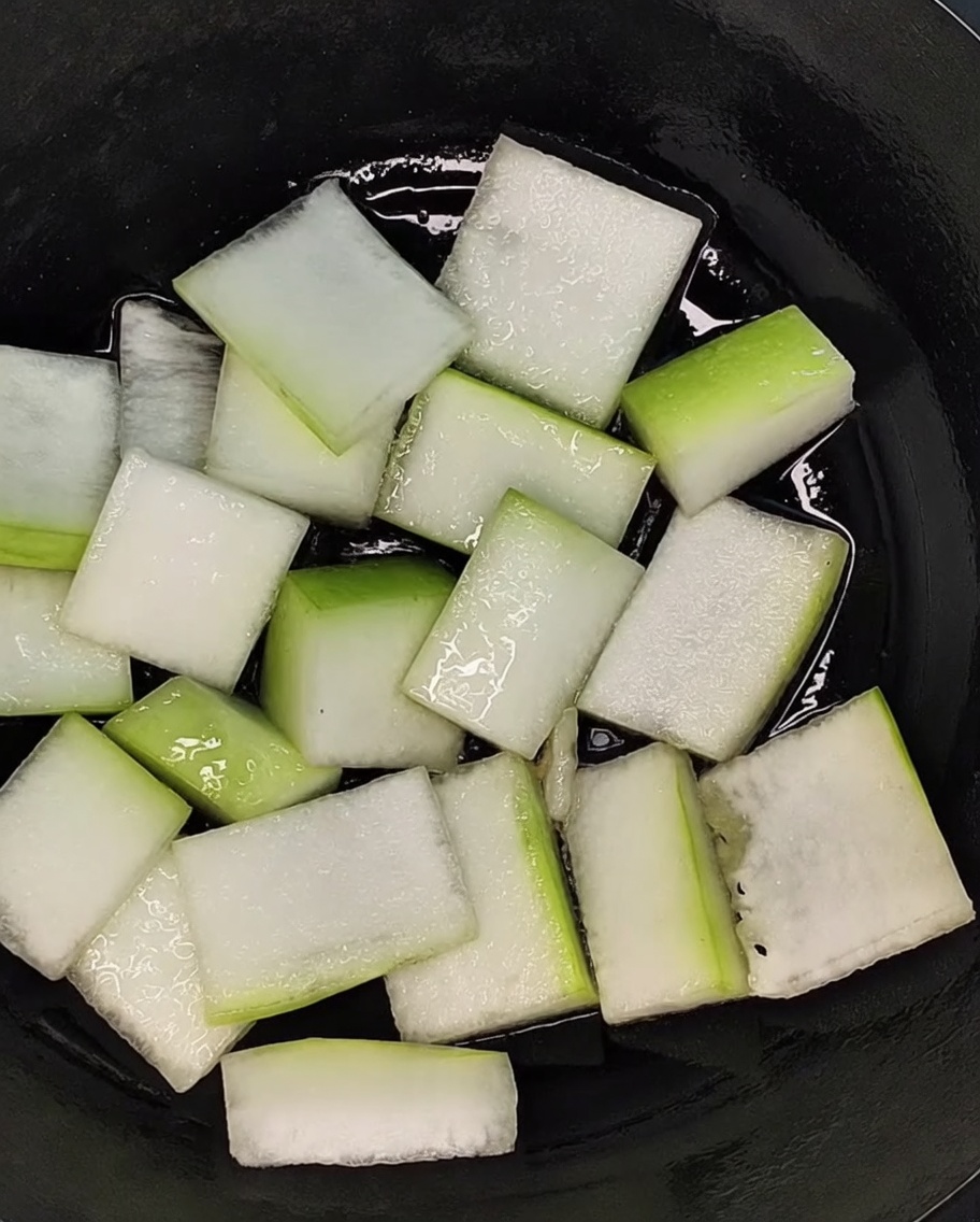 Kawałki melona zimowego ułożone na dnie garnka.