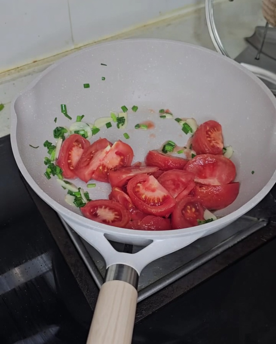 Drobno pokrojone świeże pomidory dodawane do podsmażonych przypraw.