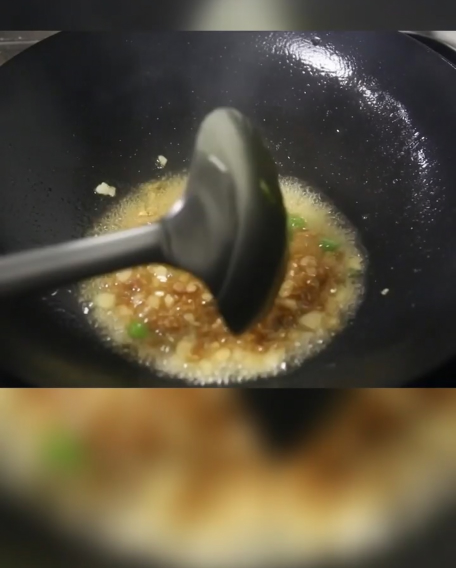 Zielona cebulka, pokrojone mięso i kostki ziemniaków smażące się na gorącej patelni z olejem.