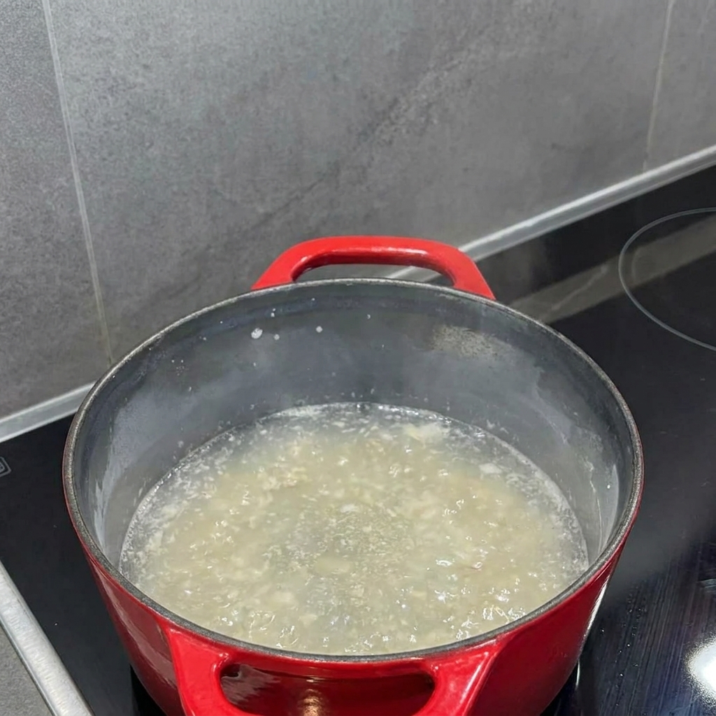 Mleko wlewane do zasmażki w garnku, mieszane na gładki płyn.