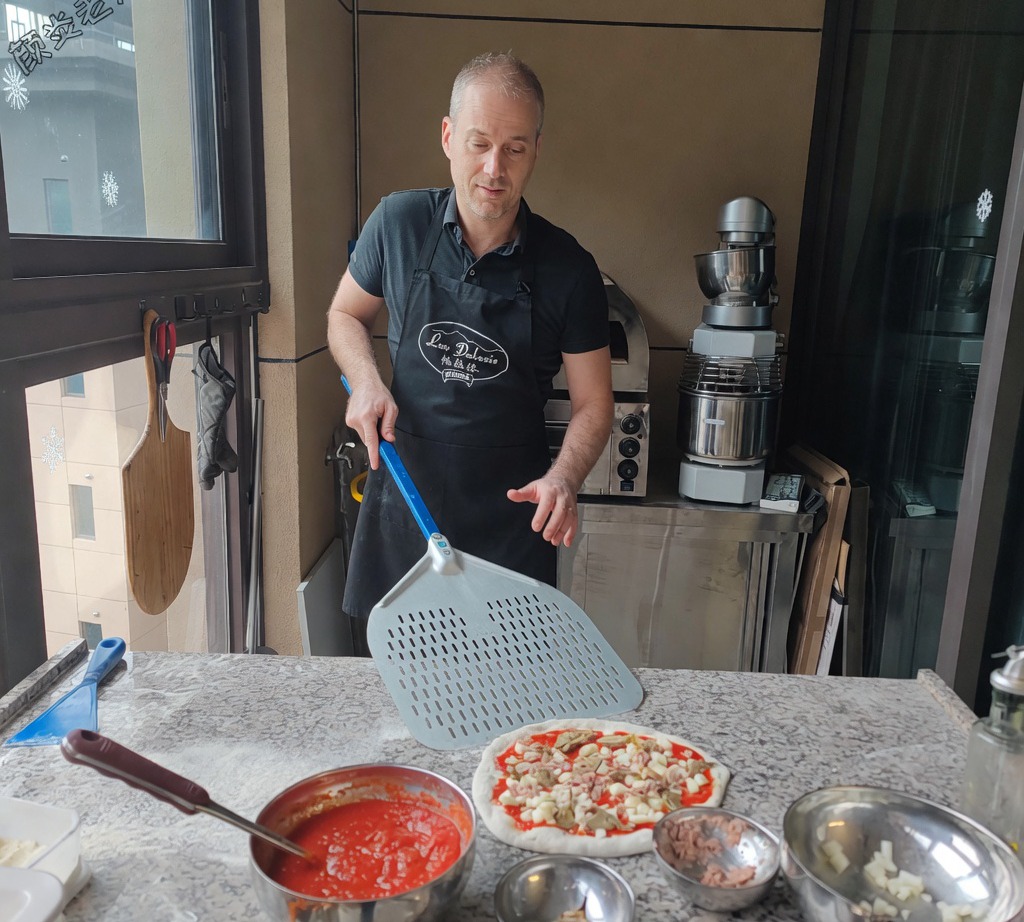 Metalowa łopatka do pizzy wsuwana pod złożoną surową pizzę, aby przygotować ją do pieczenia.