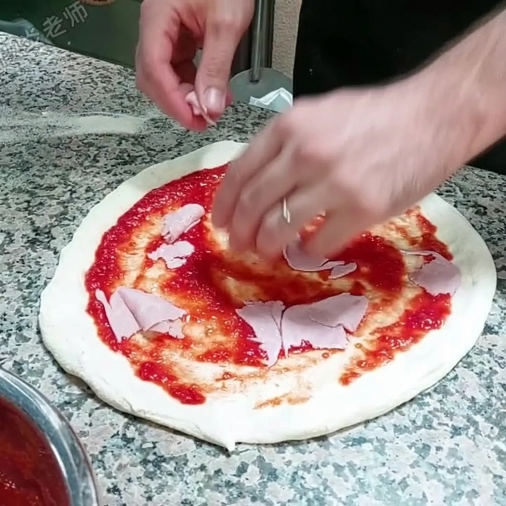 Cienkie plastry szynki układane na spodzie pizzy pokrytym sosem.