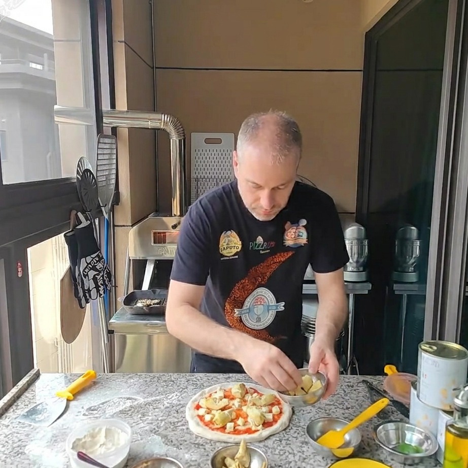 Kawałki karczochów z puszki układane na pizzy pokrytej serem.