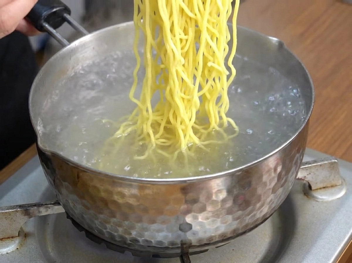 Chiński makaron ramen gotujący się w garnku z wodą.