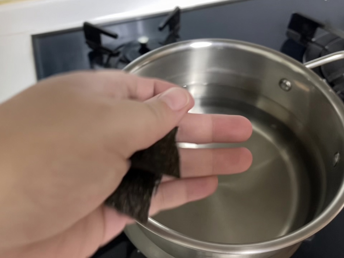 Dwa kawałki glonów kelp zanurzane w garnku ze świeżą, zimną wodą.