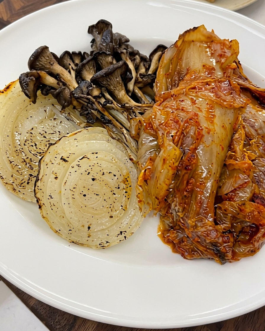 Nasiona sezamu posypywane na wierzch upieczonych warzyw i kimchi na talerzu.