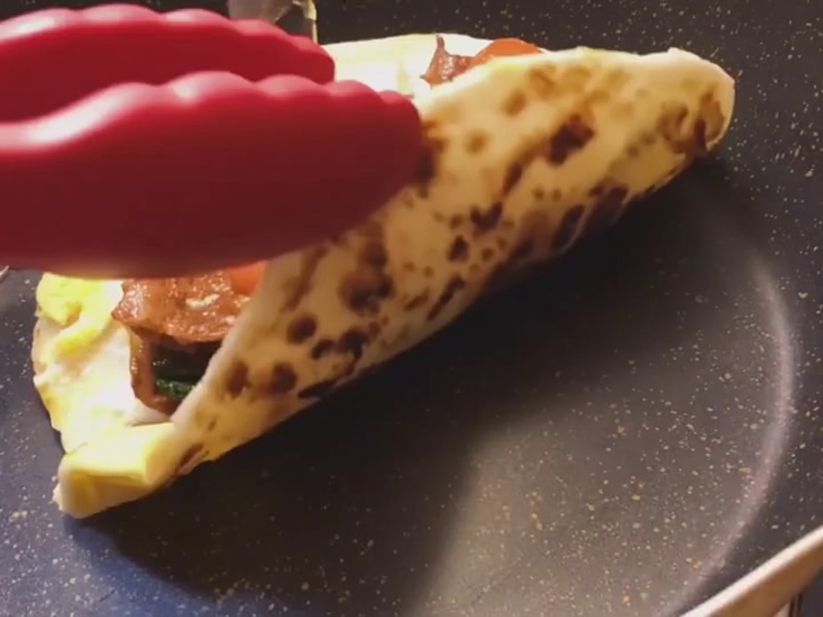 Świeżo przygotowany wrap z placka z dymką zwijany ciasno na płaskiej powierzchni.