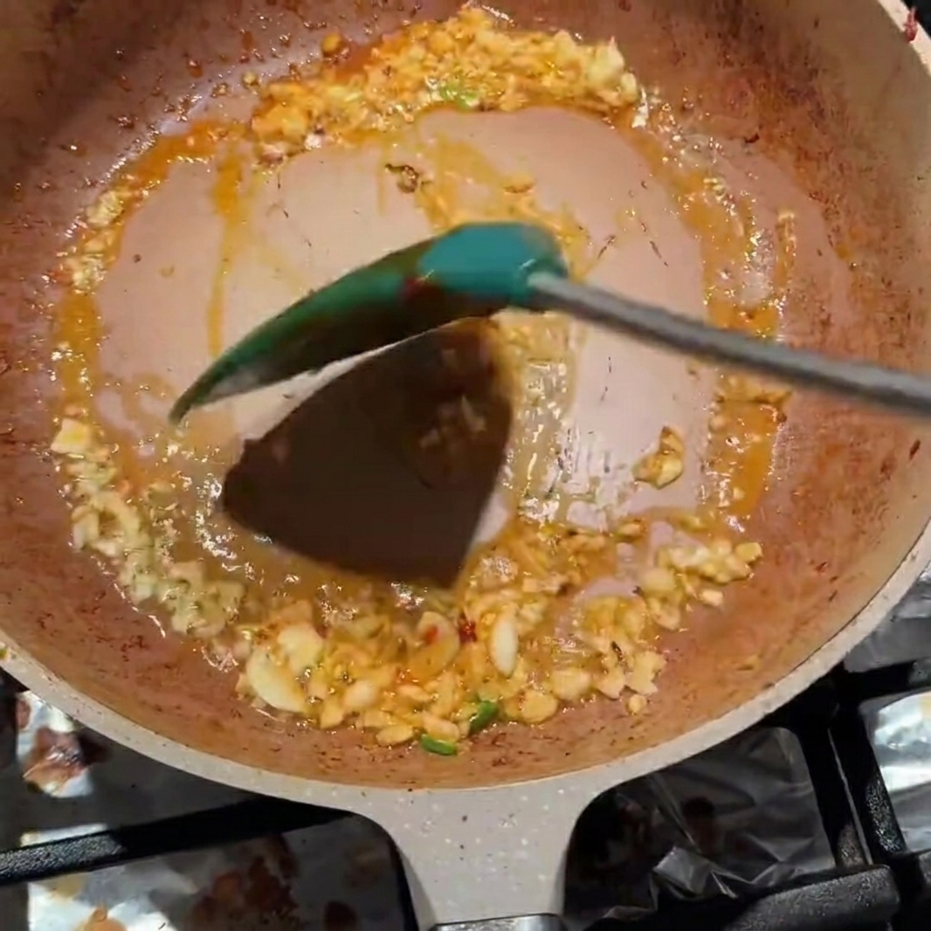 Posiekany czosnek i pasta z bobu Pixian wymieszane razem na patelni.