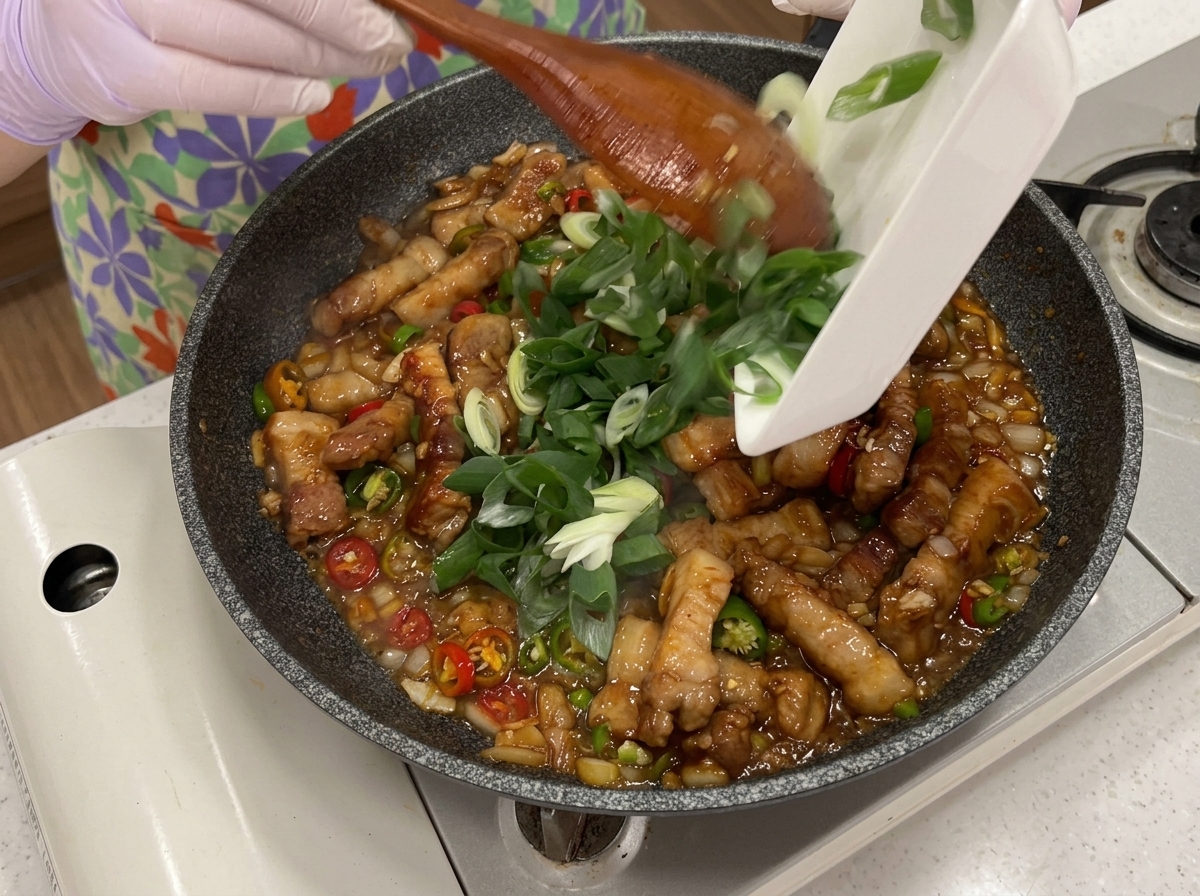 Dodawanie świeżych chili i szczypiorku do patelni.
