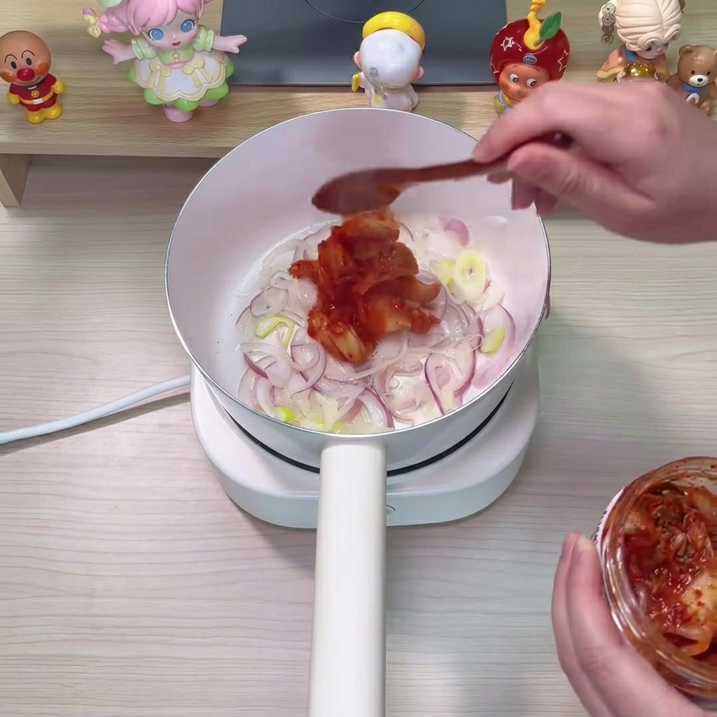 Kimchi i czerwone płatki chili mieszane z cebulą w garnku.