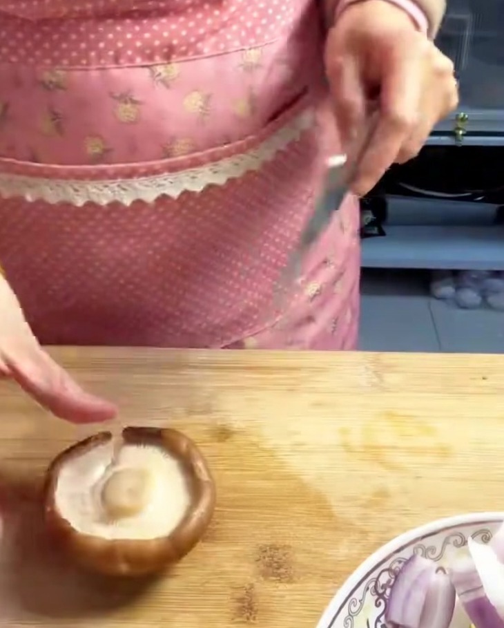 Świeże grzyby shiitake pokrojone w równe, cienkie paski na drewnianej desce.