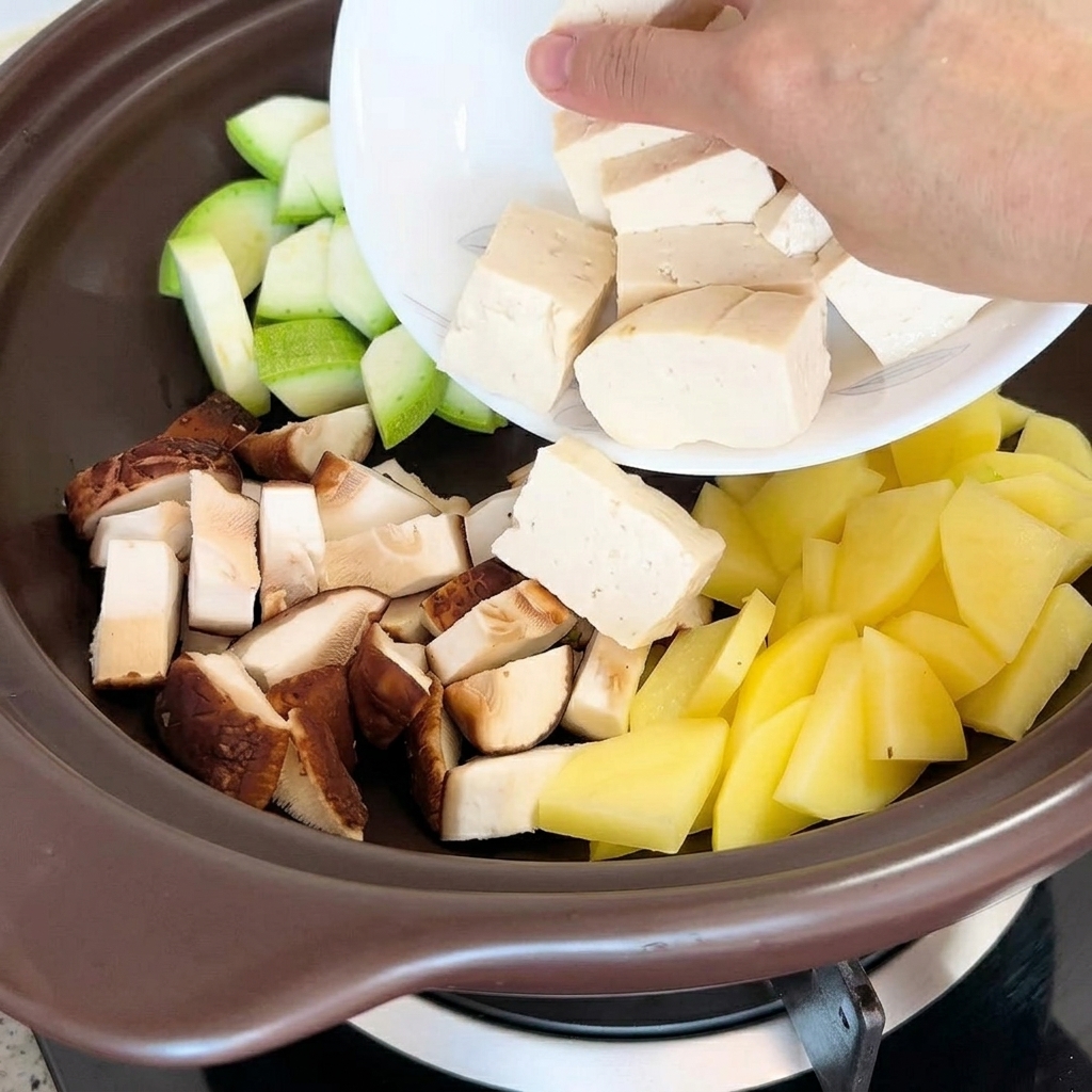 Kawałki tofu i suszone małże dodawane do garnka z warzywami.