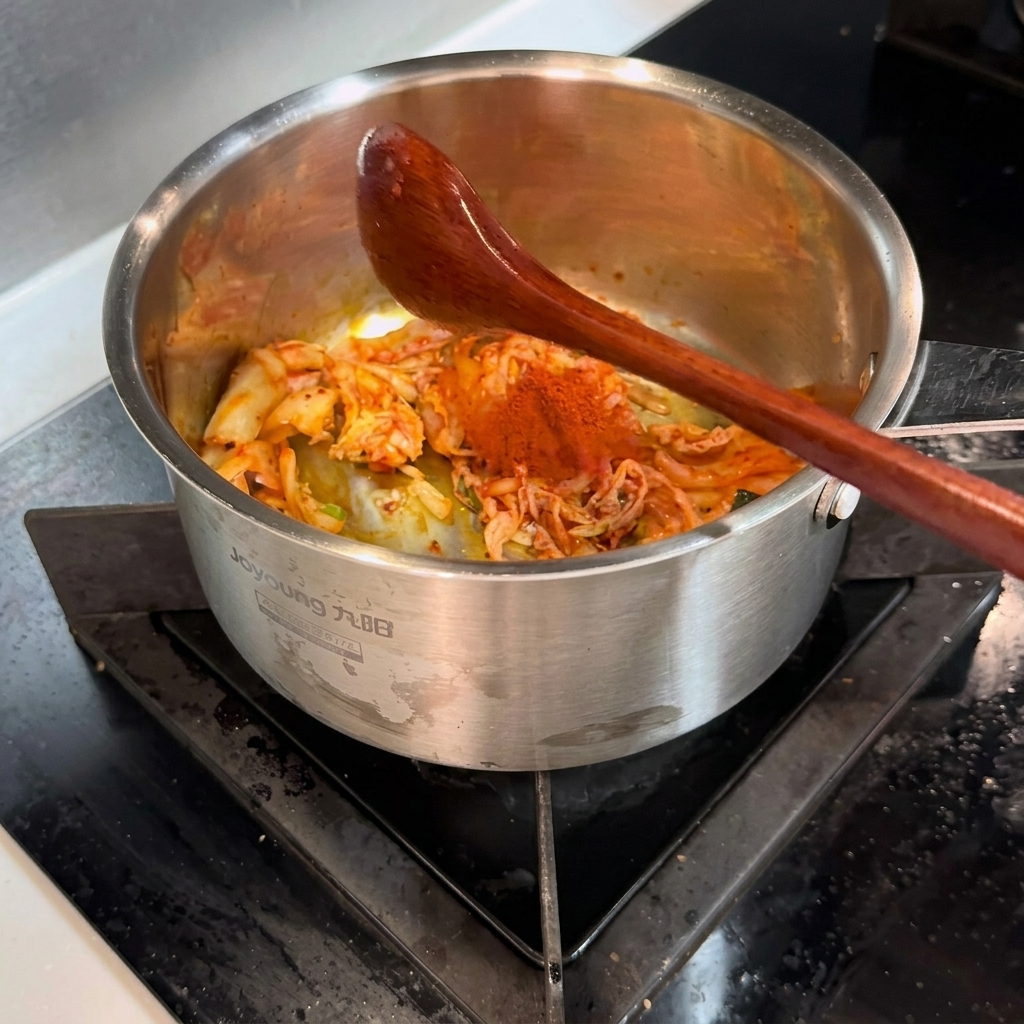 Drewniana łyżka mieszająca czerwoną paprykę w proszku z kimchi w garnku.