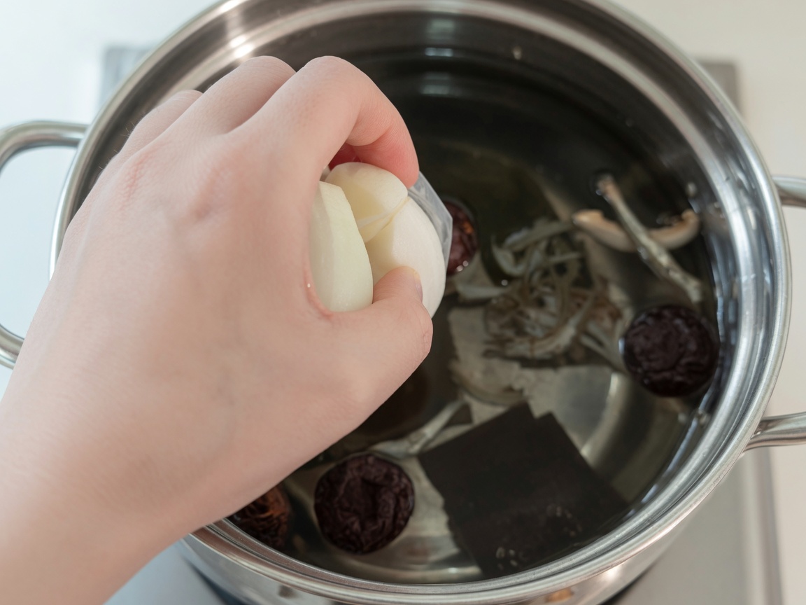 Gotująca się woda w garnku z kelp, anchois, grzybami shiitake, cebulą i rzodkiewką.