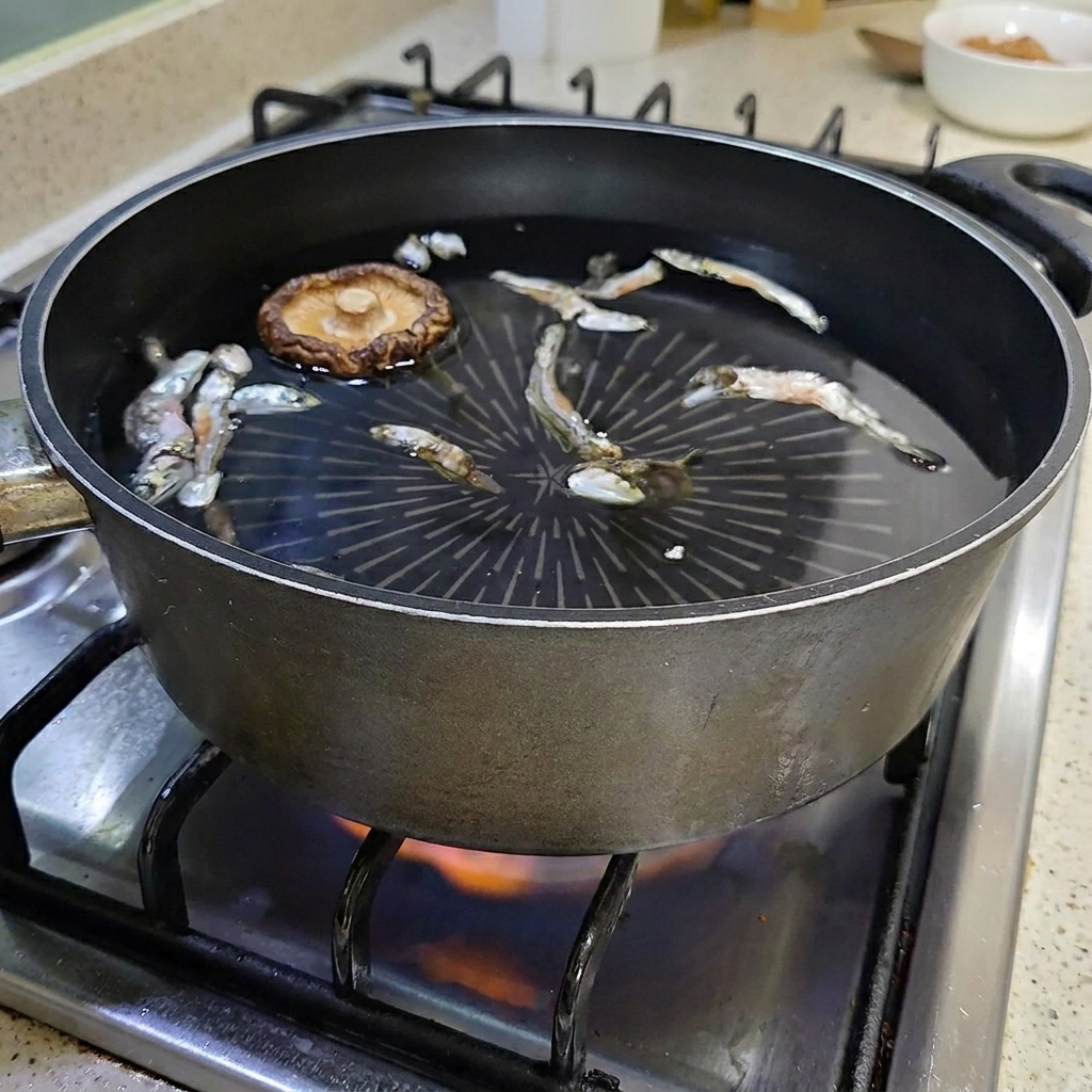 Suszony grzyb shiitake pływający w garnku z wodą i anchois.