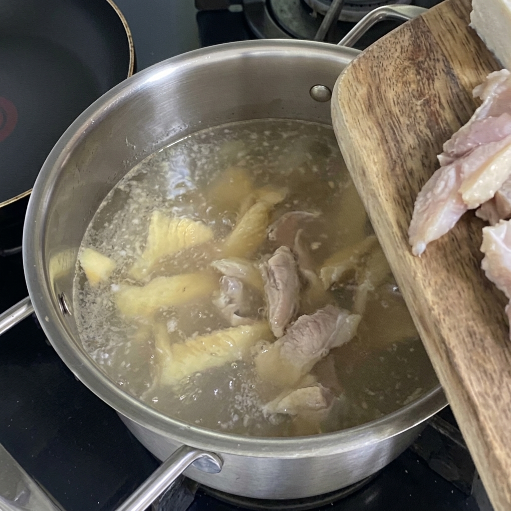 Kostki tofu wrzucane do gotującego się, jasnego wywaru z mintaja.