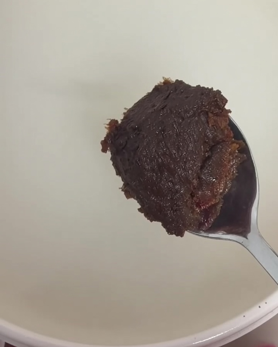 Łyżka gęstej brązowej pasty sojowej i ciemnoczerwonej pasty chili mieszana w wywarze z wody ryżowej.