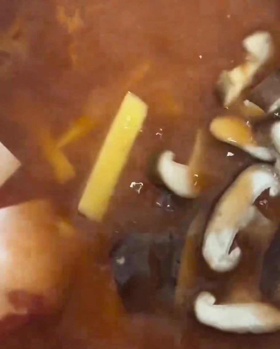 Plastry świeżych grzybów shiitake układane w gulaszu.
