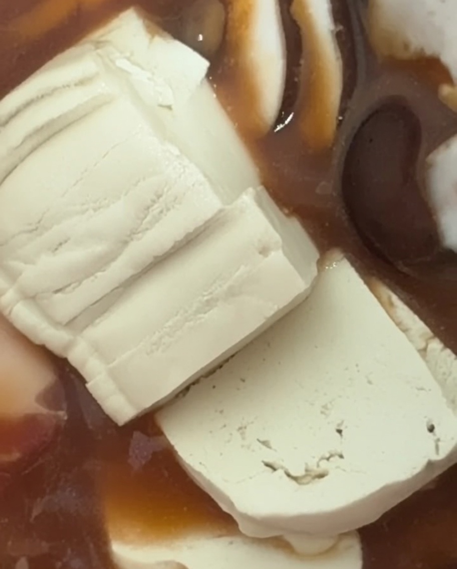 Świeże, miękkie plastry białego tofu układane w bulgoczącym gulaszu.