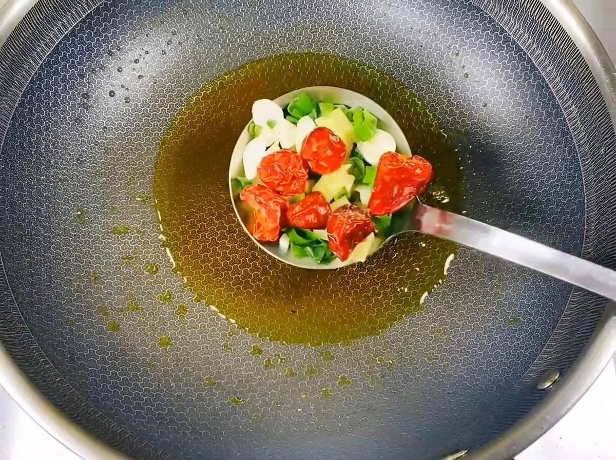 Posiekany szczypiorek, czosnek i suszone chili smażone na gorącym oleju.