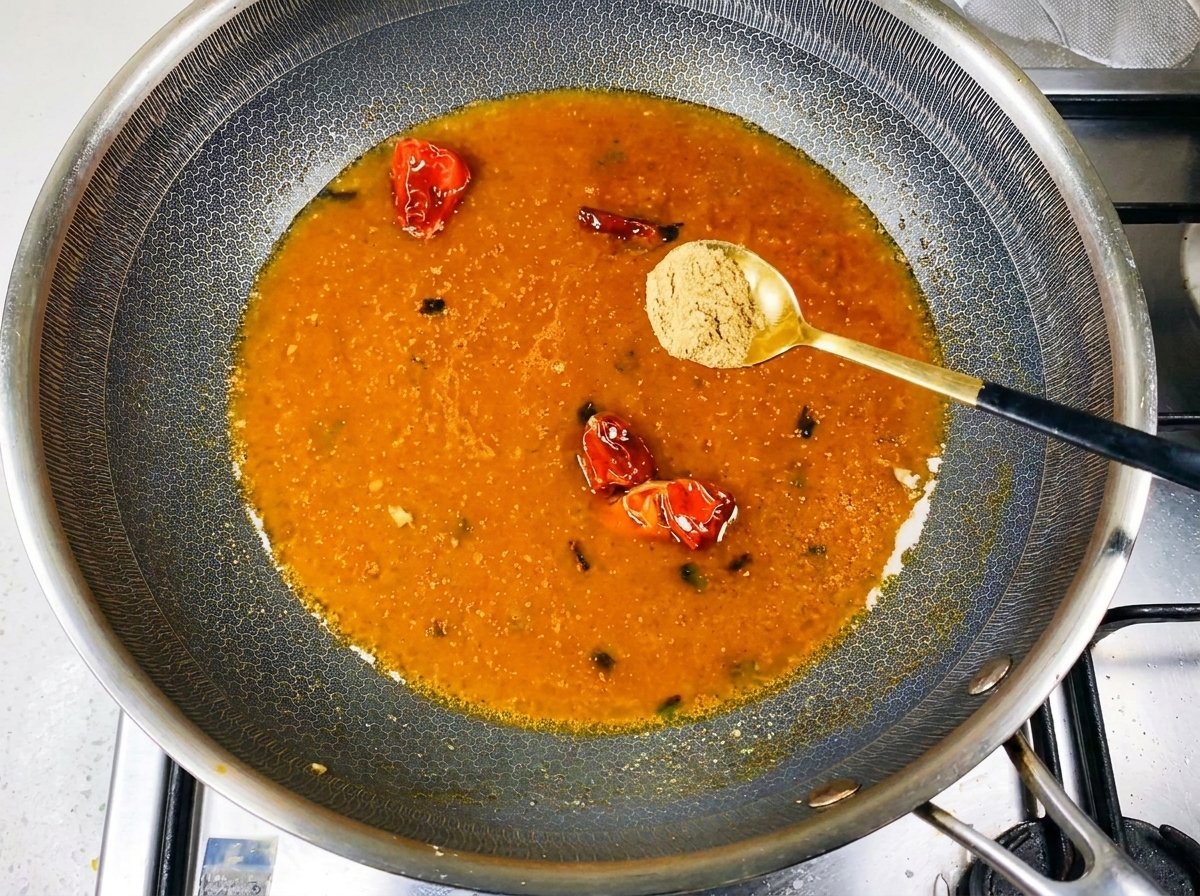 Sypanie przyprawy do gotującego się, pomarańczowego bulionu w woku.