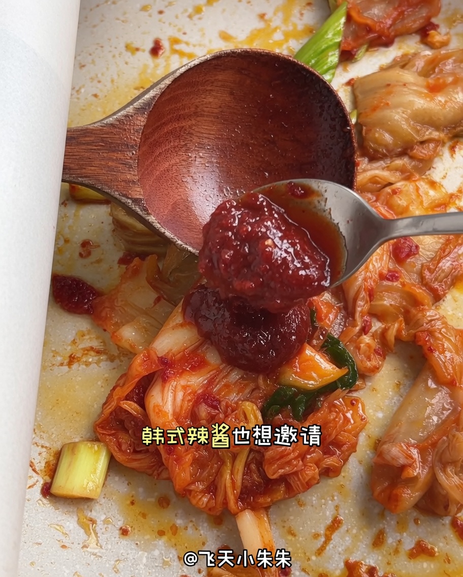 Łyżka czerwonej koreańskiej pasty chili dodawana do składników na patelni.