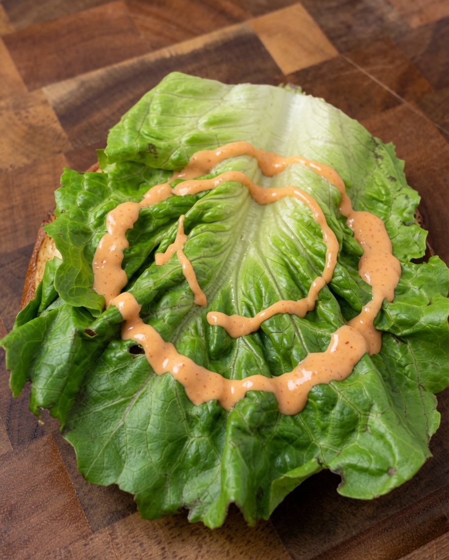 Świeży burger z warstwami sałaty, cebuli i pomidora.
