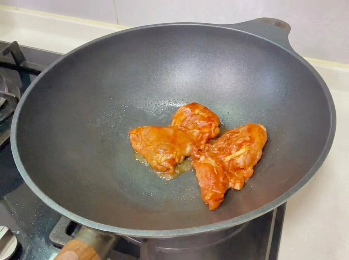 W pełni złożony burger z kurczakiem teriyaki leżący na drewnianej desce, gotowy do zjedzenia.