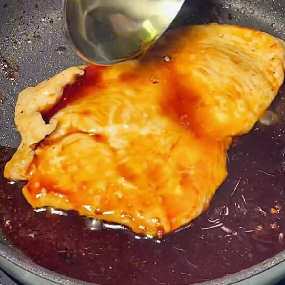Gęsty sos teriyaki wylewany na złotego kurczaka na patelni.