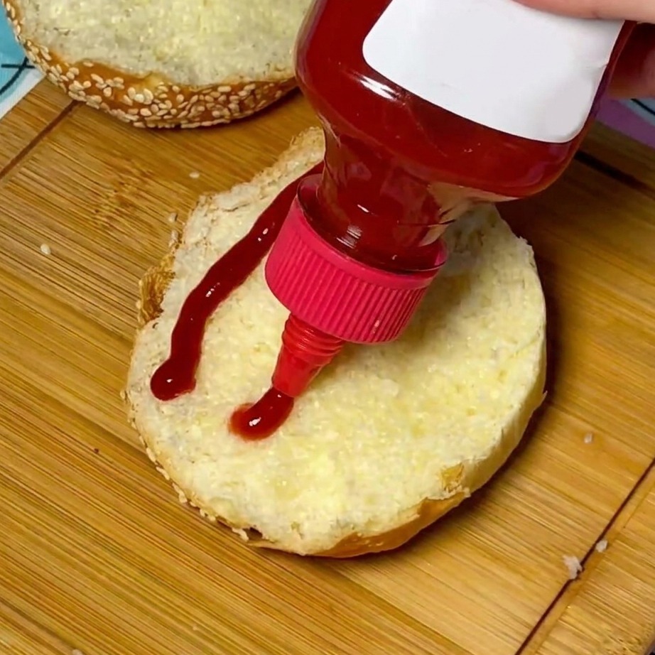 Ketchup wyciśnięty na środek tostowanej bułki z sezamem.