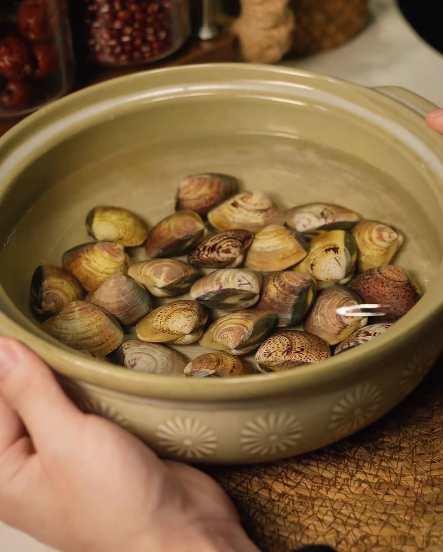 Świeże małże moczące się w ceramicznej misce z wodą w celu usunięcia piasku.