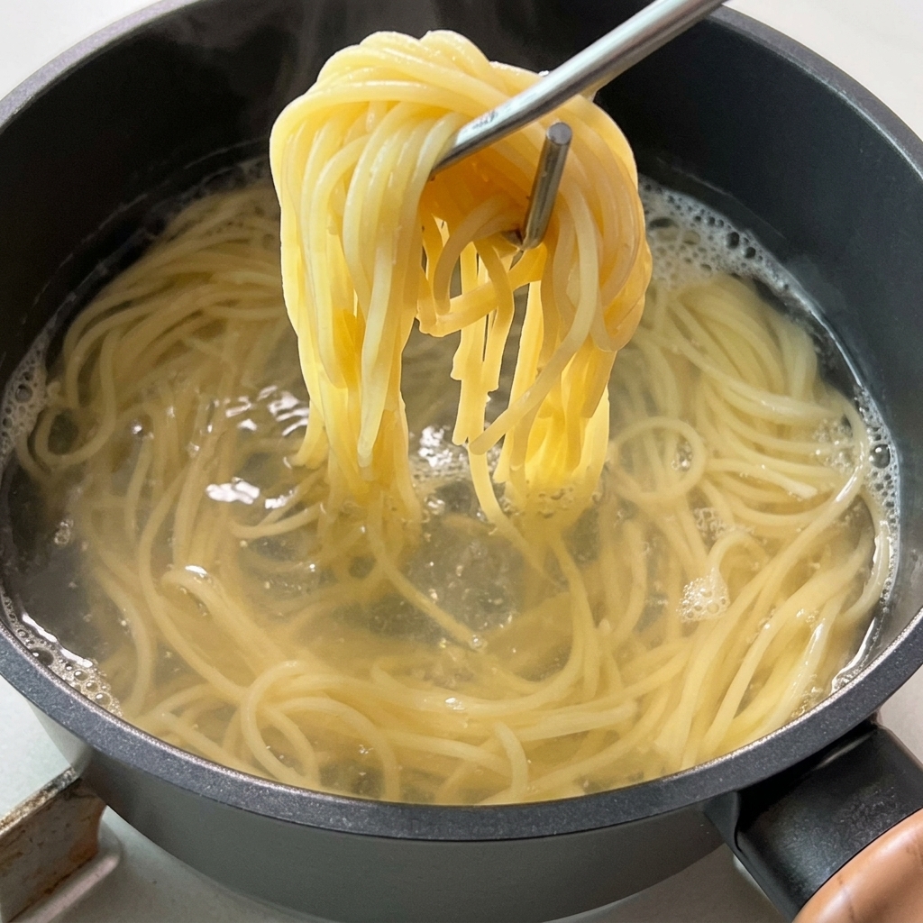 Szczypce wyjmujące dużą porcję ugotowanego spaghetti z garnka z wrzącą wodą.