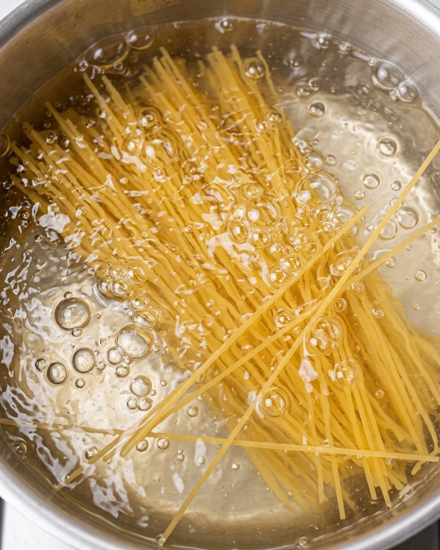 Makaron spaghetti gotujący się w garnku z wrzącą wodą.