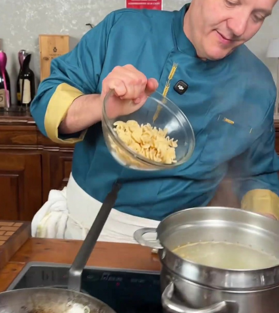 Makaron fusilli wrzucany do dużego garnka z gotującą się wodą.