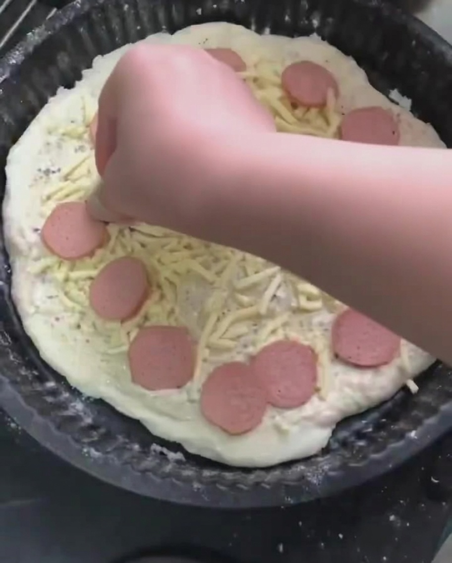 Plastry kiełbasy układane na warstwie mozzarelli.
