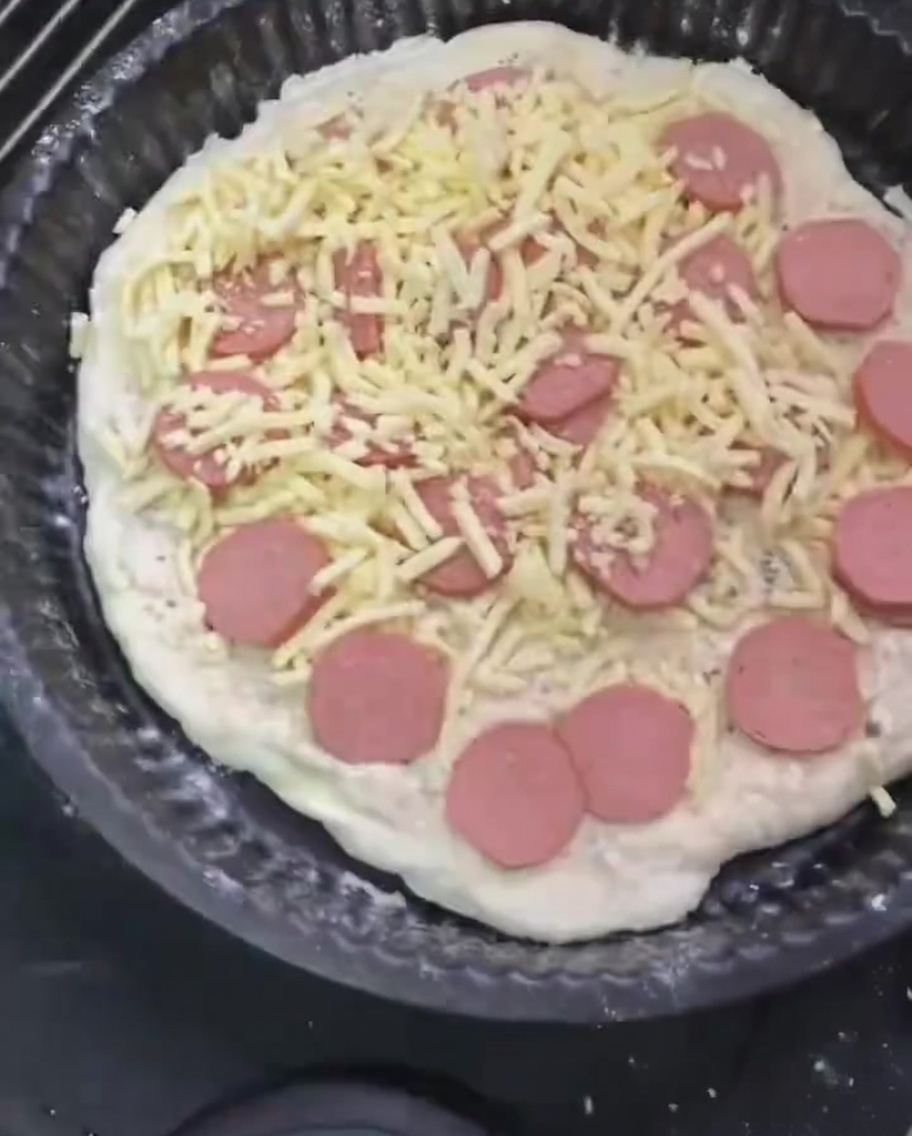 Dodatkowa porcja mozzarelli posypywana na wierzch pizzy z kiełbasą.