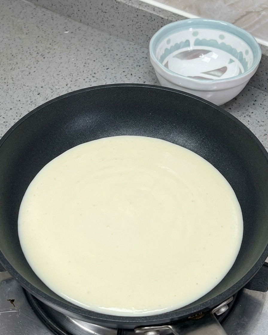 Śmietanka, mleko, masło i pasta mentaiko podgrzewane razem na patelni.