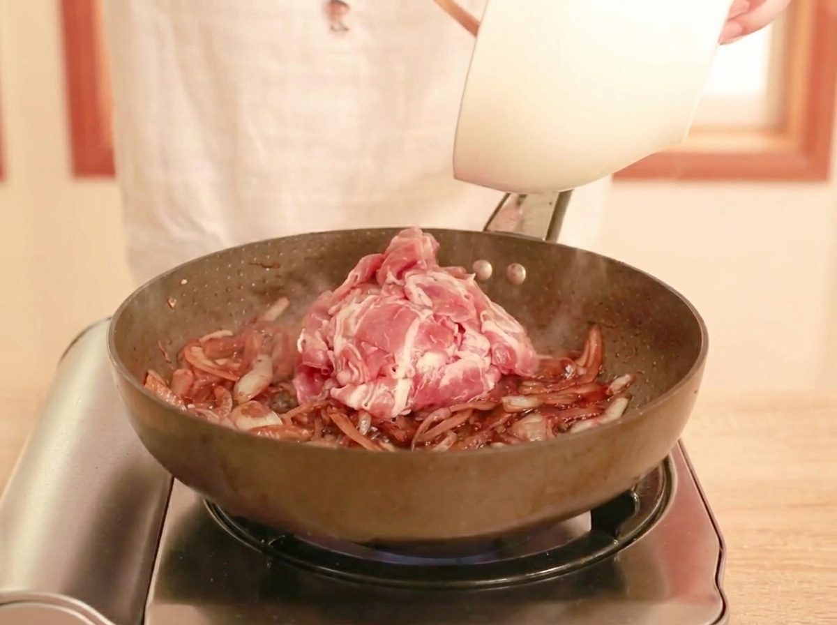 Surowa wołowina dodawana na patelnię z sosem i cebulą, gotowa do stir-fry.