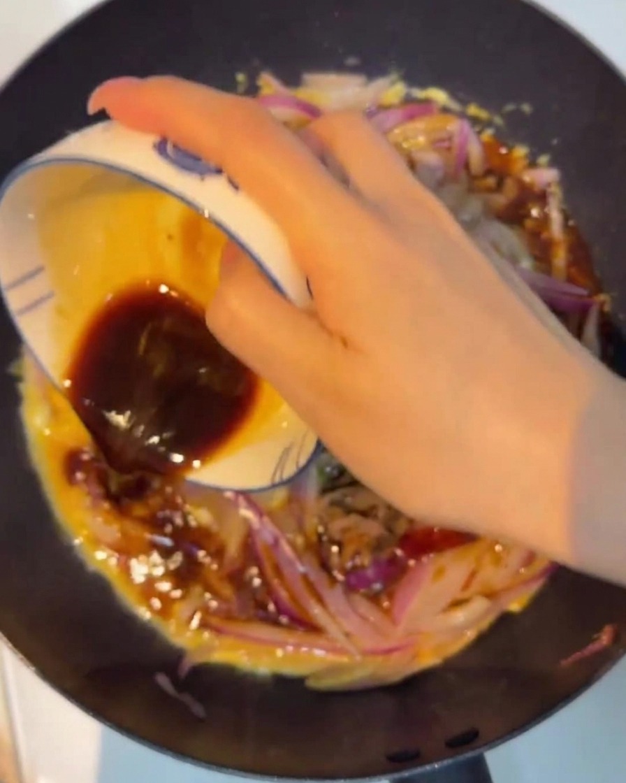 Ciemny sos wylewany na stir-fry z wołowiny, cebuli i jajek.