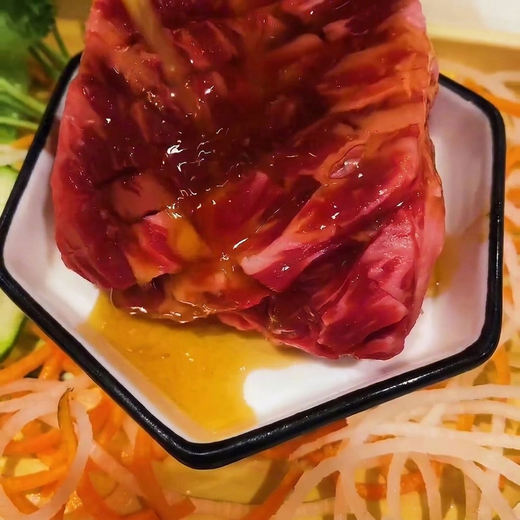 Sos w stylu koreańskim polewany na kawałek surowego żebra wołowego w małym białym naczyniu.