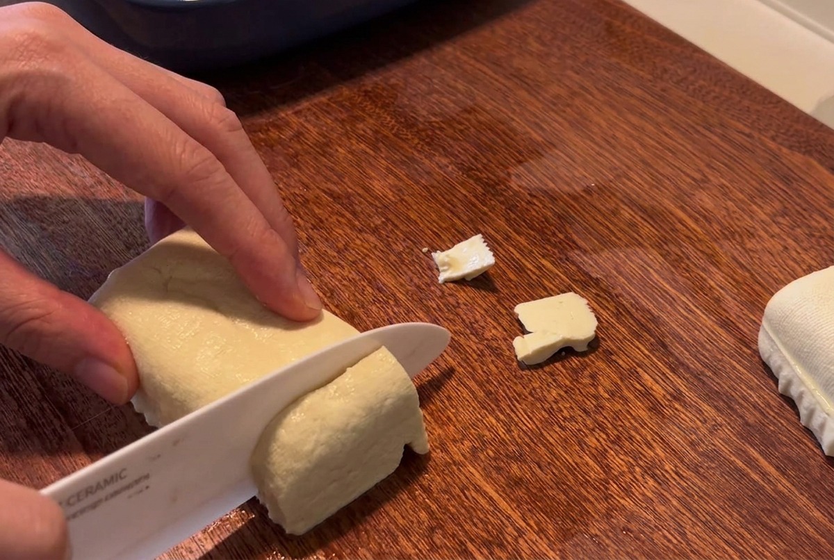 Blok twardego białego tofu krojony w kostkę na drewnianej desce.