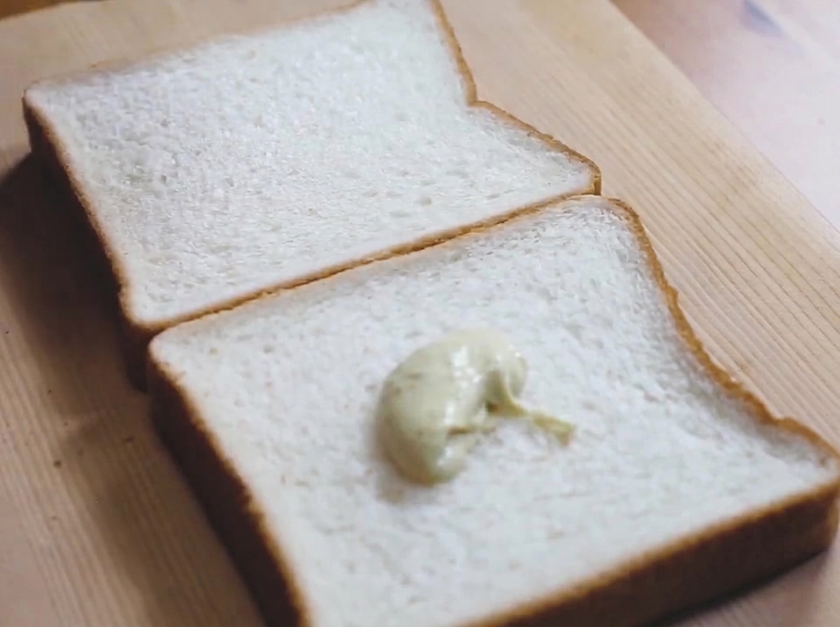 Porcja jasnozielonego sosu majonezowo-wasabi na kromce białego pieczywa.