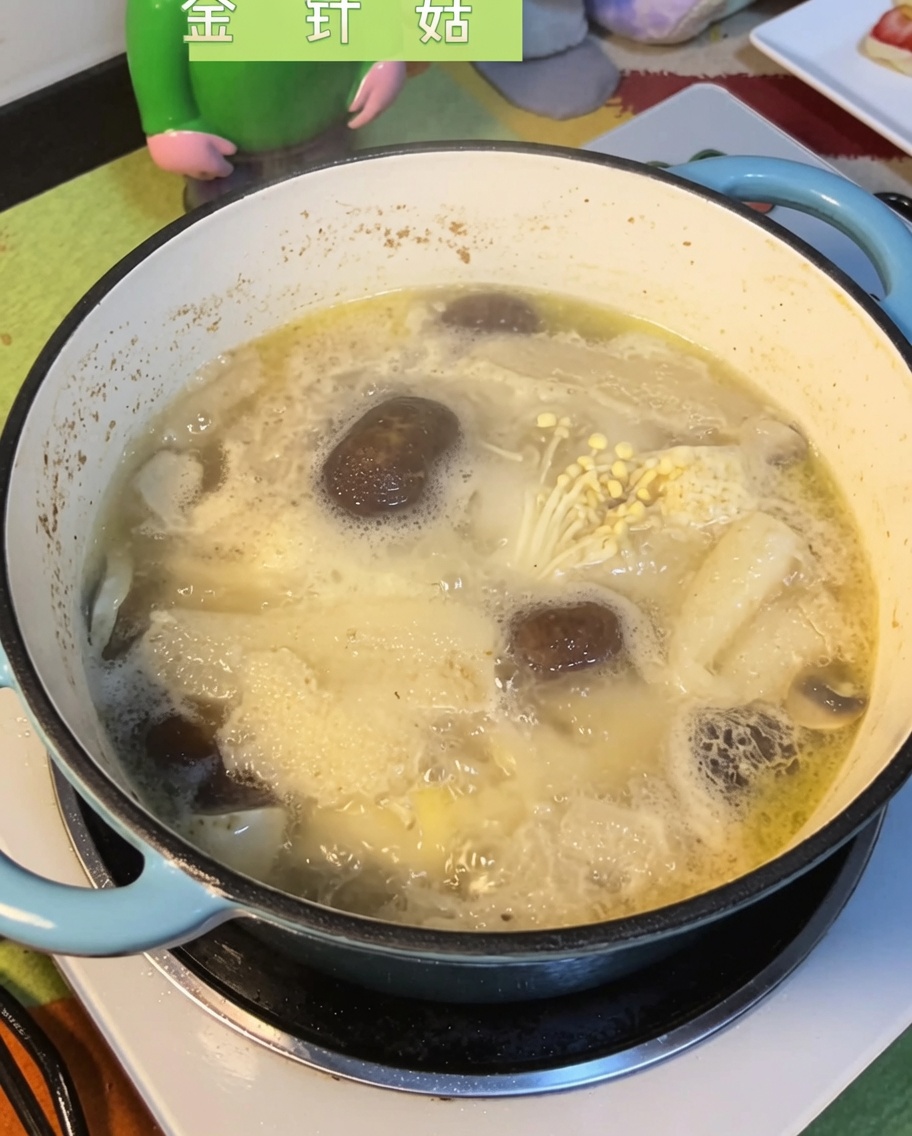 Grzyby enoki zanurzane w bulgoczącym bulionie z kurczaka i grzybów.