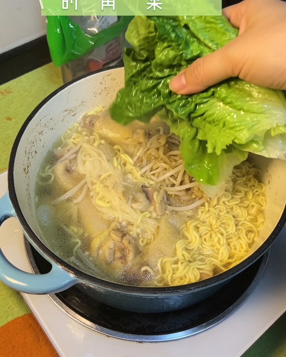 Świeże liście zielonego bok choy dodawane do gotowej zupy.