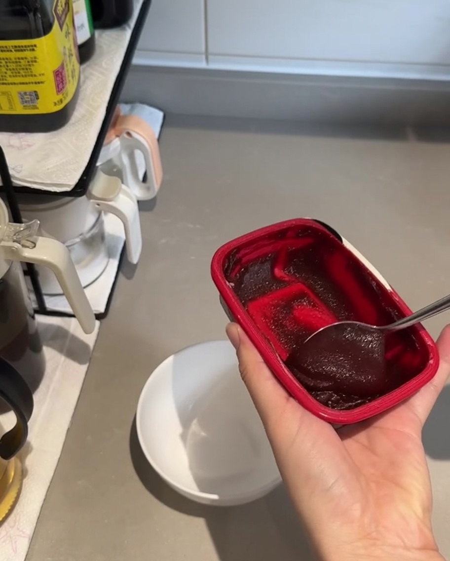 Mała biała miseczka z dużą łyżką ciemnoczerwonej pasty gochujang i sosem sojowym, gotowe do wymieszania.