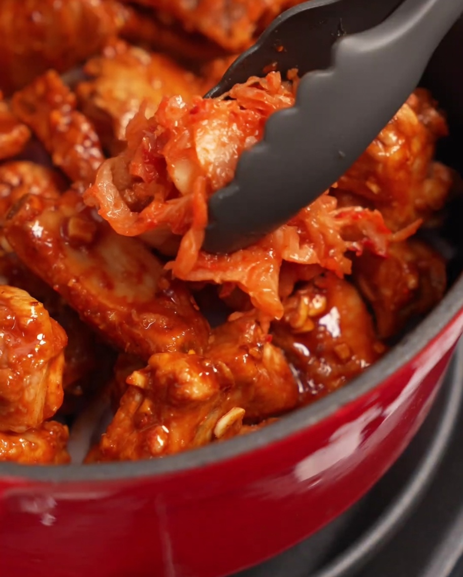 Porcja czerwonego kimchi układana na żeberkach w garnku.
