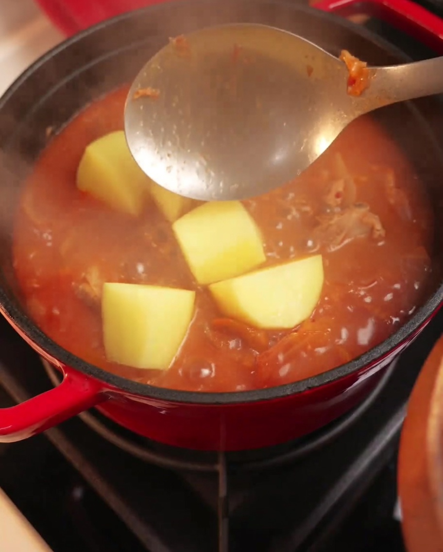 Kawałki ziemniaków dodawane do gotującego się gulaszu z kimchi i żeberkami.