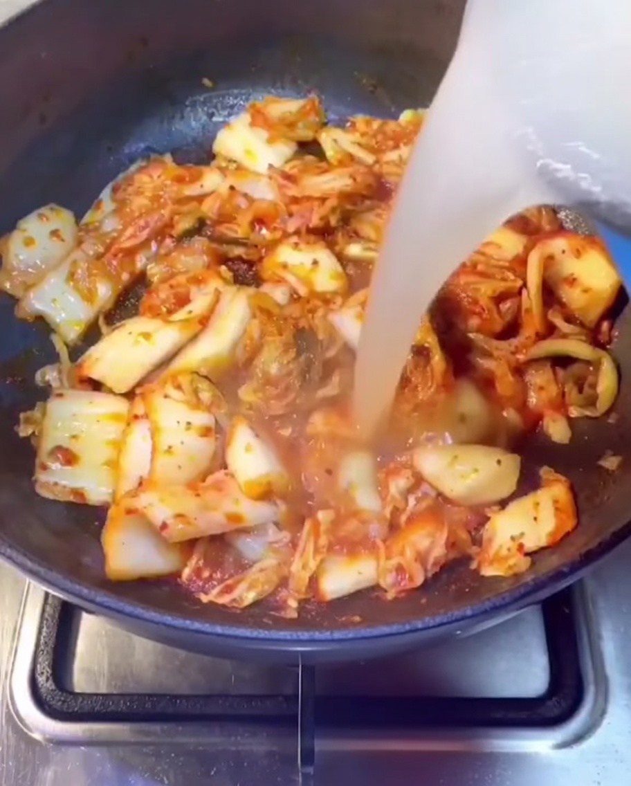Wywar z żeberek wlewany na patelnię z podsmażonym kimchi.